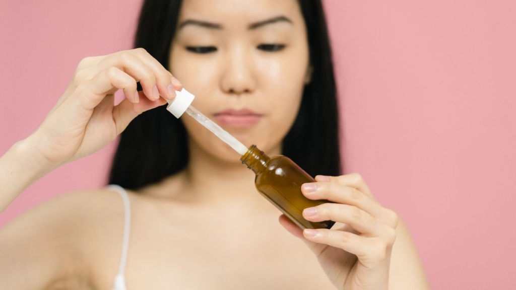 Damlalıklı şişeden yüzüne anti aging serum uygulayan kadın