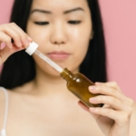Damlalıklı şişeden yüzüne anti aging serum uygulayan kadın