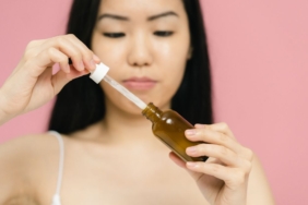 Damlalıklı şişeden yüzüne anti aging serum uygulayan kadın