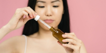 Damlalıklı şişeden yüzüne anti aging serum uygulayan kadın