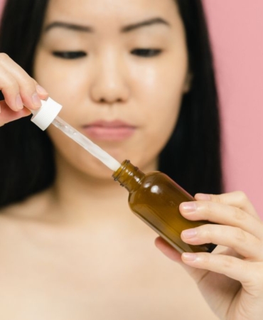 Damlalıklı şişeden yüzüne anti aging serum uygulayan kadın