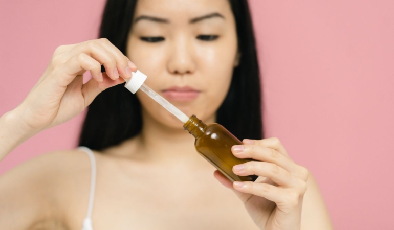 Damlalıklı şişeden yüzüne anti aging serum uygulayan kadın