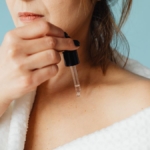 Aynada göz çevresindeki ince çizgilere serum uygulayan kadın