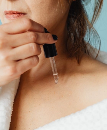 Aynada göz çevresindeki ince çizgilere serum uygulayan kadın