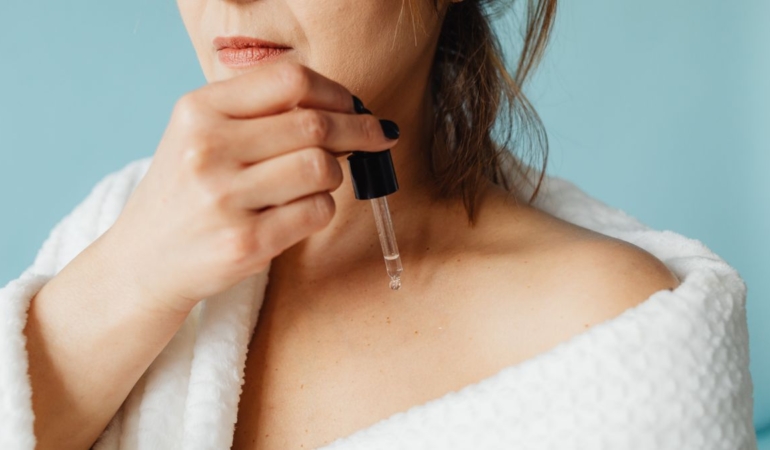 Aynada göz çevresindeki ince çizgilere serum uygulayan kadın